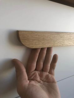 a person's hand is reaching up to the wall with a wooden object on it