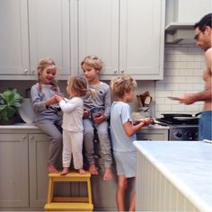 a group of people standing in a kitchen next to a yellow stepladder with pots and pans on it