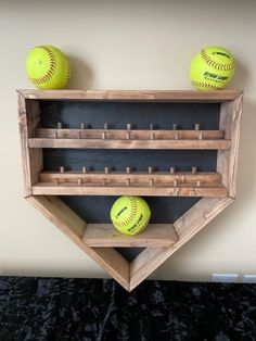 two softballs are sitting on top of a wooden shelf that holds three baseballs