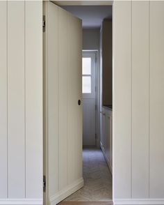 an open door leading to a hallway with white walls and wood floors in a home