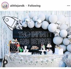 a table topped with white balloons next to a chalkboard sign that reads, the infinitity and beyond