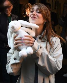 a woman holding a white stuffed animal in her hands