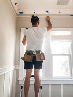 a man is working on the ceiling in his house with paint rollers and tools