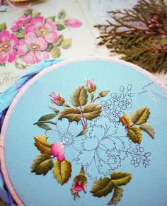 some pretty blue and pink flowers are on the table next to other items that have been embroidered onto them