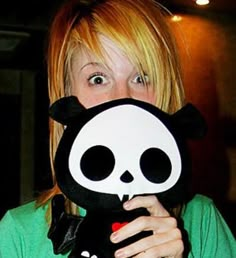 a woman holding up a panda bear mask to her face