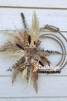 an arrangement of dried flowers and feathers on a wall