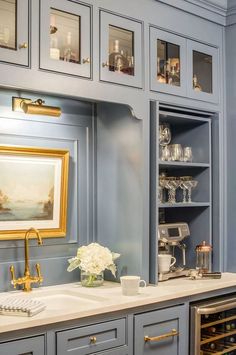 a kitchen with blue cabinets and white flowers in vases on the sink countertop