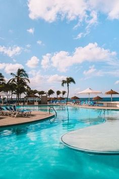 an empty swimming pool with lounge chairs and umbrellas