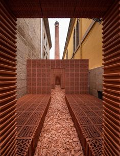 an open brick wall in the middle of a courtyard with red bricks on each side