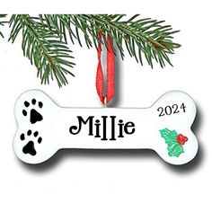 a personalized dog bone ornament hanging from a christmas tree with paw prints