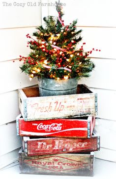 a christmas tree is sitting on top of some old coca - cola crates in front of a house