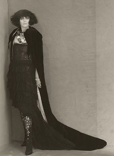 an old fashion photo of a woman wearing a long black dress and cape with sequins