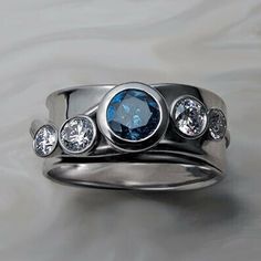 a silver ring with blue and white stones on it's sides, set against a gray background