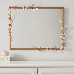 a white dresser with a mirror and flowers on it