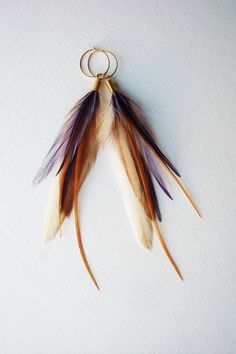 a keychain with feathers hanging from it's side on a white surface