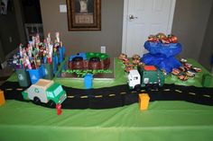 a table topped with cakes and toys on top of a green table cloth