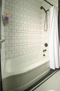 a white bath tub sitting next to a toilet and shower head mounted on a wall