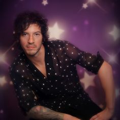 a man with tattoos on his arm posing in front of a purple background and stars