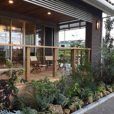 an outside deck with chairs and plants on the ground next to it in front of a building