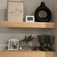 two wooden shelves with pictures and vases on them