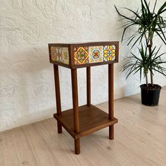 a potted plant sitting on top of a wooden stand next to a white wall