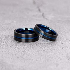 two black and blue wedding rings sitting on the ground