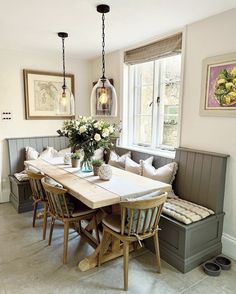 a dining room table and bench with flowers in vases on the centerpiece next to it