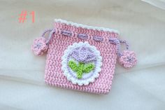 a pink crocheted purse with a flower on the front and green leaves on the outside