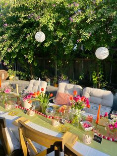 a table with flowers and candles on it in the middle of a patio area surrounded by greenery