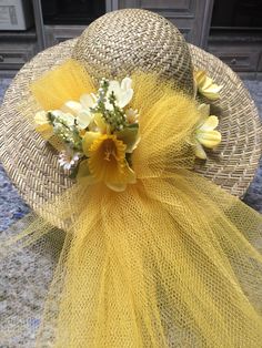 a straw hat with yellow flowers on the front and side, sitting on a granite surface