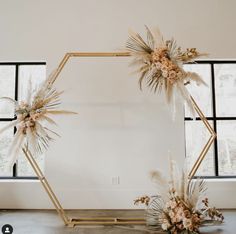 an arch decorated with dried flowers and pamodia in front of a large window