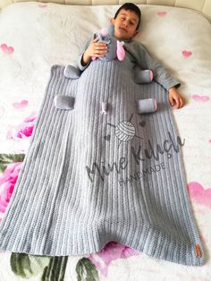 a little boy laying on top of a bed covered in a blanket with an elephant