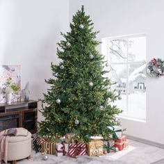 a christmas tree in the corner of a living room with presents on the floor next to it