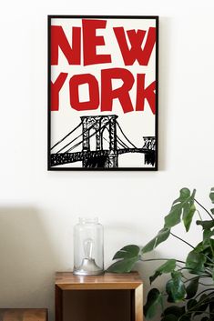 a painting hanging on the wall above a table with a plant in front of it