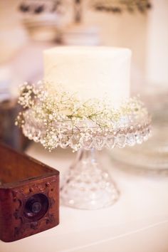 a white cake sitting on top of a table next to a wooden box filled with flowers