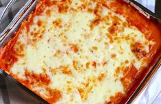 a square casserole dish with cheese and sauce in it on a checkered table cloth