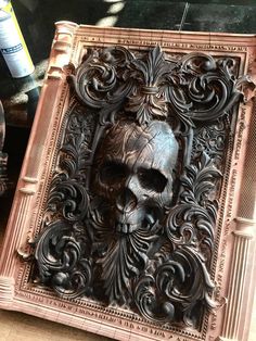 an intricately carved wooden frame with a skull in it's center is shown