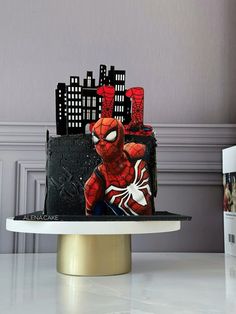 a spiderman cake on top of a table with cityscape in the background