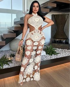 a woman standing in front of a staircase wearing a white dress with sheer cutouts