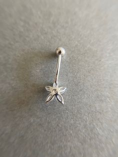 a silver nose ring with a bee on it's end, sitting on a gray surface