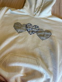 a white hoodie with blue and black designs on the front is laying on a bed