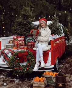 a woman sitting on the back of a red truck with christmas decorations and presents in it