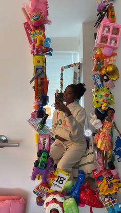 a woman sitting on top of a pile of toys in a room next to a window