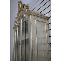 an antique china cabinet with glass doors and gold trimmings on the top shelf