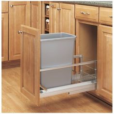 a kitchen with wooden cabinets and an open trash can in the middle of the cabinet