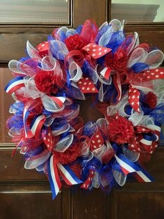 a red, white and blue wreath is hanging on the front door with an american flag bow