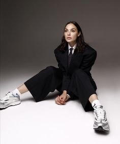 a woman is sitting on the floor with her legs crossed and wearing white tennis shoes