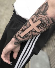 a man with a cross and roses tattoo on his arm