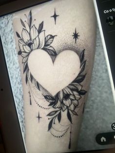 a black and white photo of a heart with flowers on the side of a woman's leg