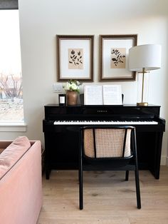 a living room with a couch, piano and two pictures on the wall above it